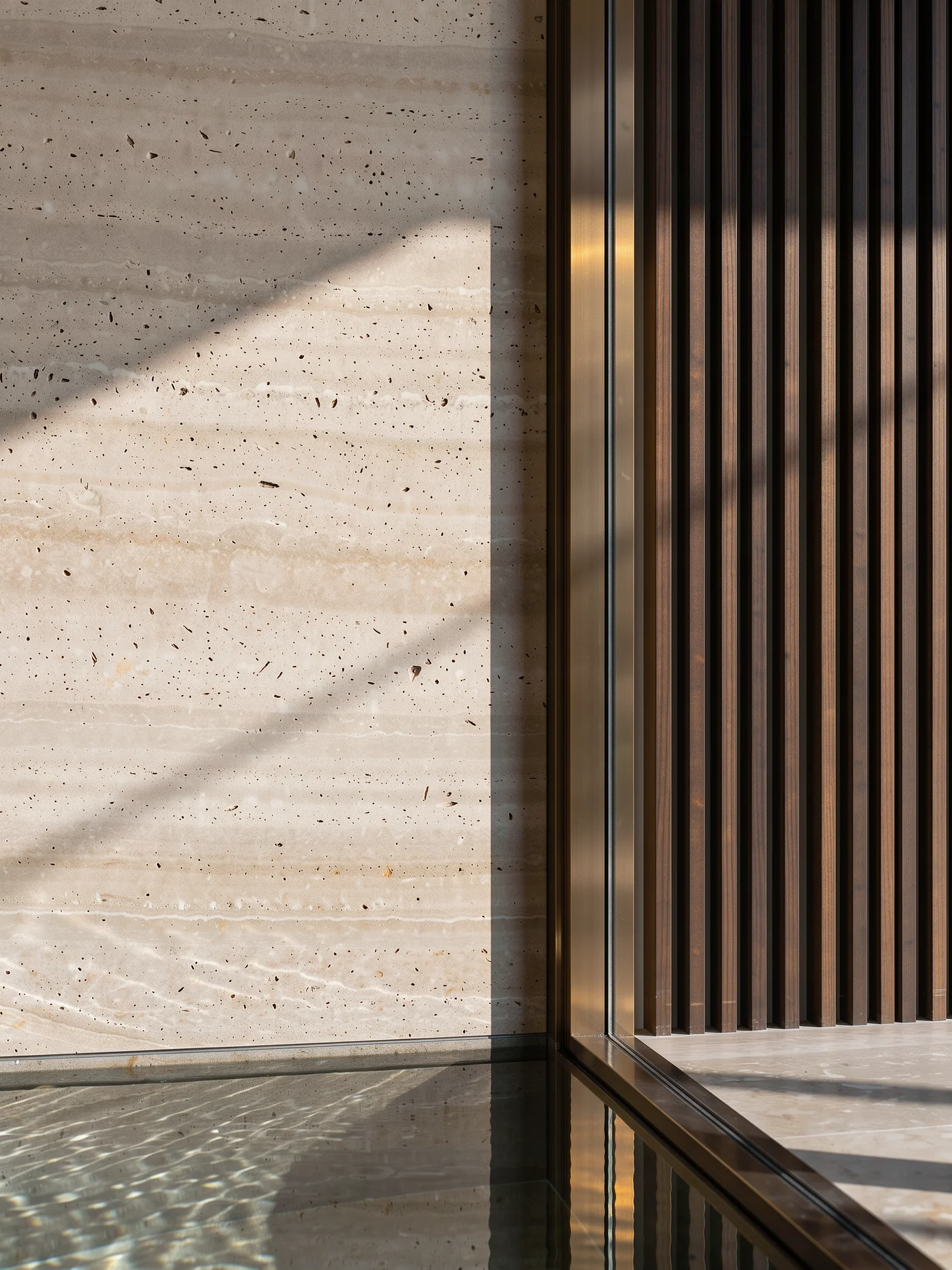 Detalle conceptual del encuentro entre piedra natural y madera, iluminado de lado